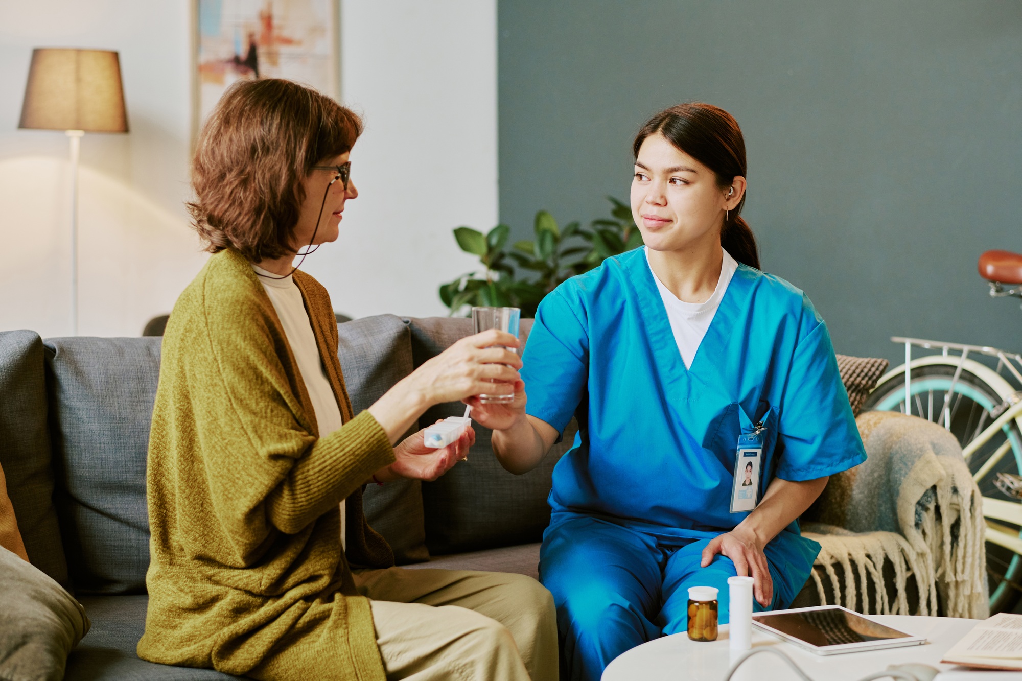 Nurse Offering Medication to Elderly Patient in Living Room